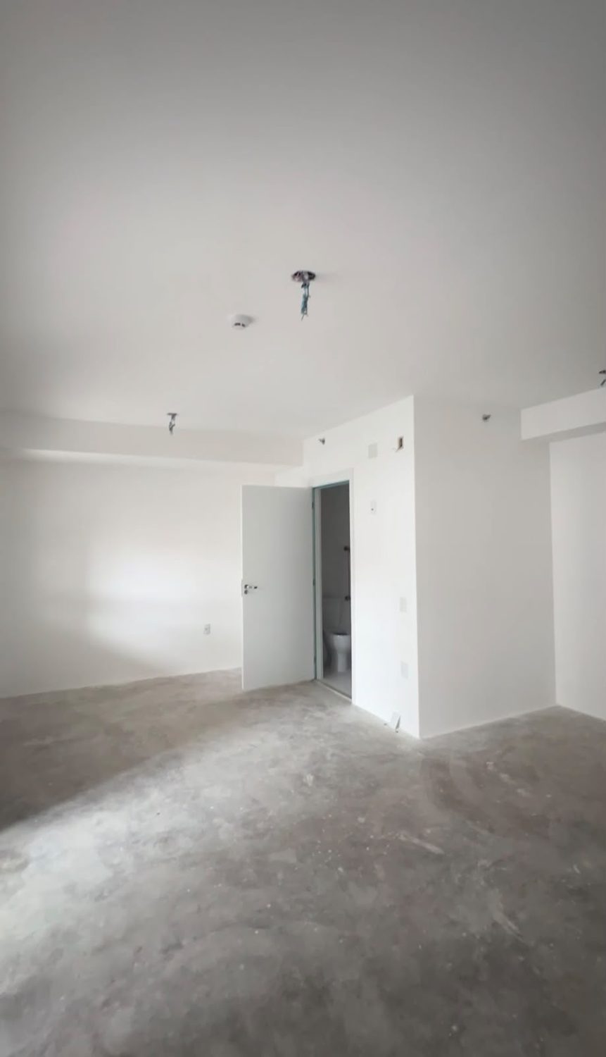 Studio LV antes da reforma, vazio, com piso de contrapiso e paredes brancas